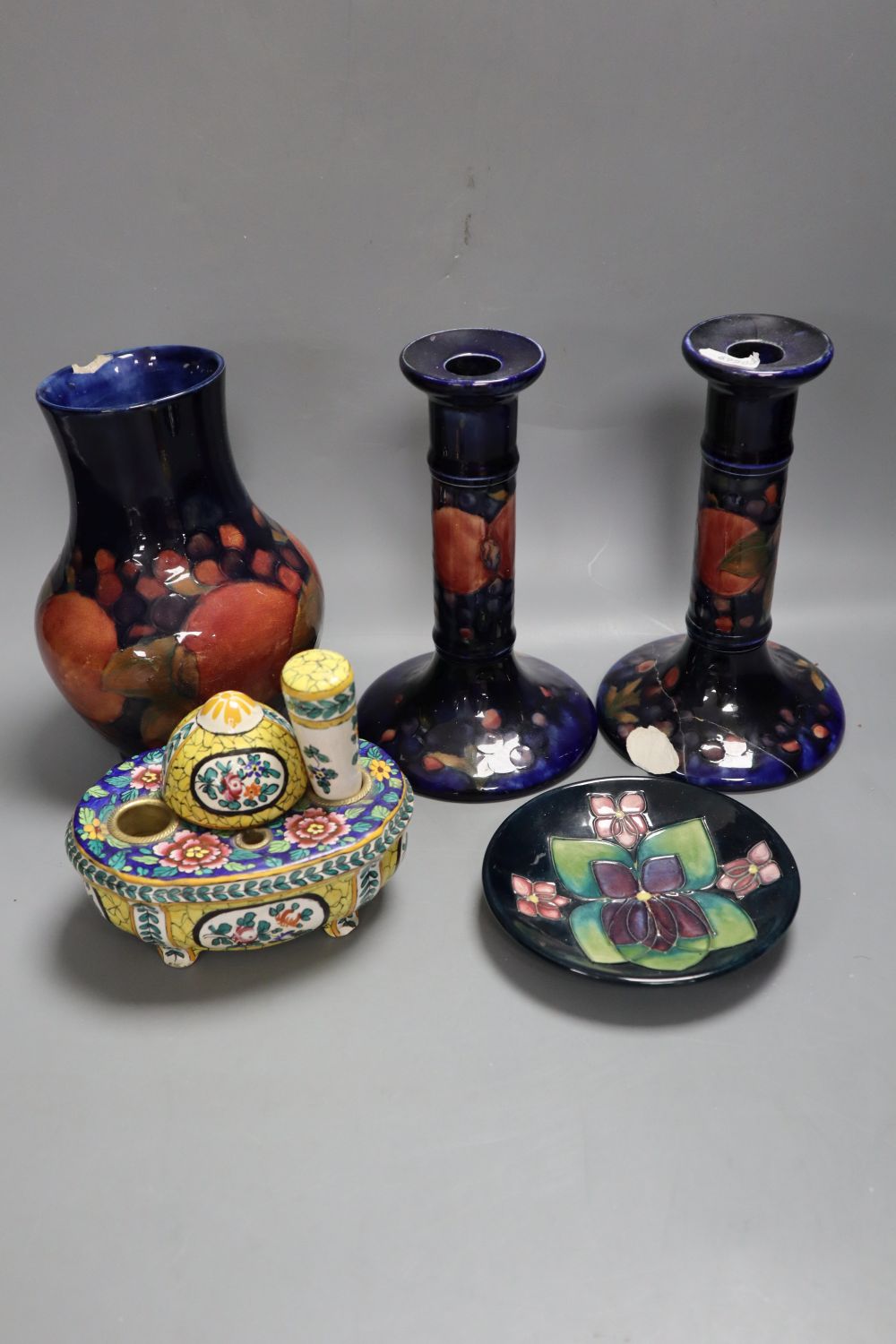 A Moorcroft bulbous vase and a pair of candlesticks, Pomegranate pattern, 18cm, a modern Moorcroft dish and a painted faience desk set,